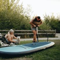 Couple with dogs, pumping up inflatable paddleboard