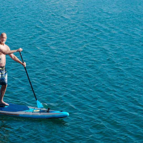 Man standing on a paddleboard on the water looking at the camera