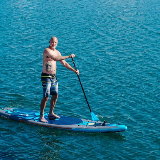 Man standing on a paddleboard on the water looking at the camera