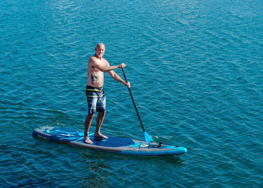 Man standing on a paddleboard on the water looking at the camera