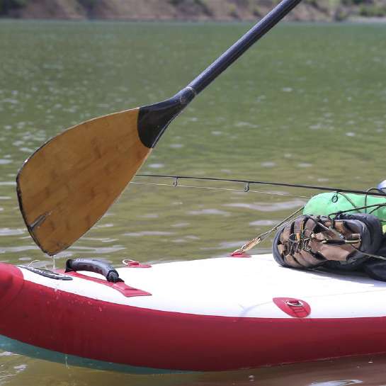 Close-up of SUP board on water with fishing gear