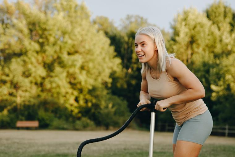 Woman inflating paddleboard with manual pump